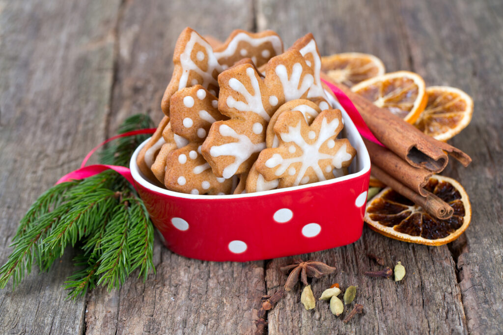 Decorated Christmas cookies in a beautiful red bowl on an old wooden background